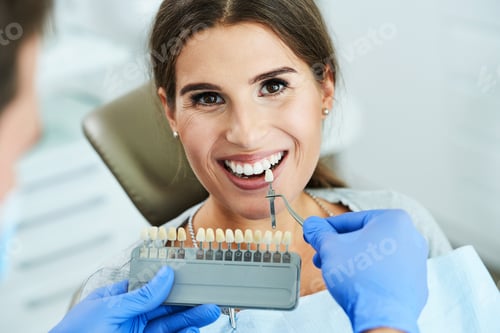 Preview: Male dentist and woman choosing tooth shade in dentist office