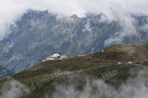Preview: Magnificent mountain peak is adorned with a large building, with clouds above