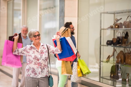 Preview: one mature woman at the mall going shopping with her husband - senior hiolding some bags smiling