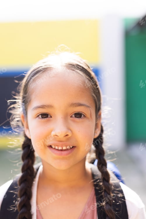 Preview: Vertical portrait of smiling cauasian elementary schoolgirl in school playground, copy space