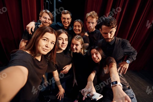 Preview: Making selfie. Group of actors in dark colored clothes on rehearsal in the theater
