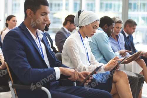 Preview: Side view of diverse business people using digital tablet during seminar in office building