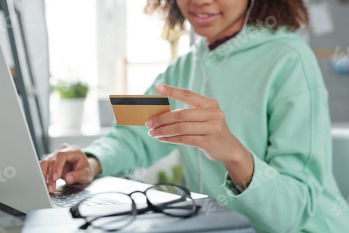 Preview: Hands of young female going to pay by credit card for purchase in online shop