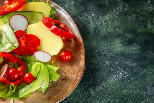 Preview: Above view of fresh peeled cut potatoes with red pepper radishes green tomatoes in a brown plate on
