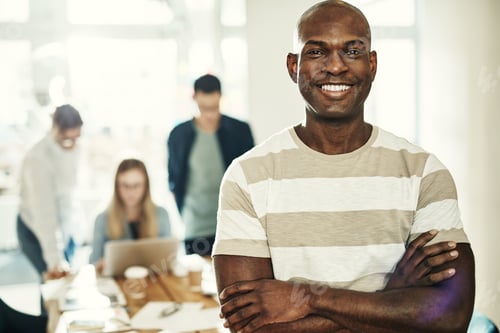 Preview: Smiling African designer with colleagues at work in the background