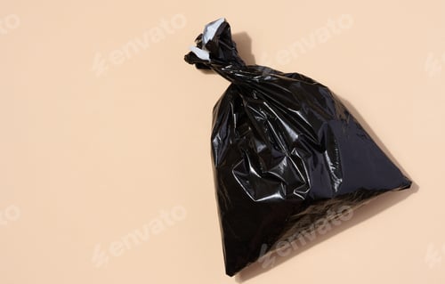 Preview: Full black plastic bag on a beige background, top view