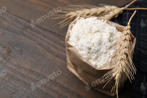 Preview: Wheat flour and spikes on wooden table, closeup. Space for text