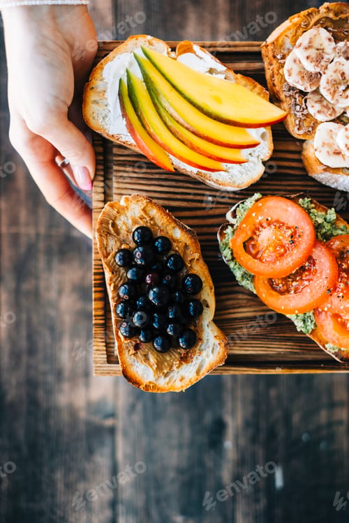 Preview: Delicious healthy toasts mix for breakfast, lunch or snack on a wooden board in hands.