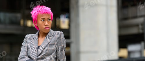 Preview: Young rebellious Asian businesswoman with pink hair thinking outdoors