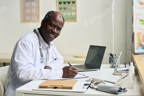 Preview: Smiling Doctor Sitting at Desk with Medical Equipment