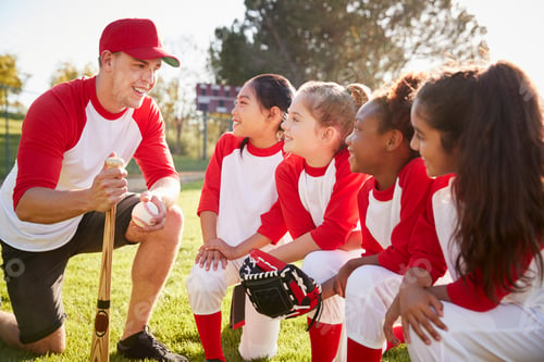 Preview: Girl baseball team kneeling in a huddle with their coach