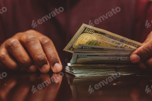 Preview: African American or black man at home counting money wealth and saving concept