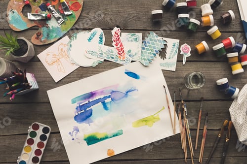 Preview: Top view of artist sketches drawn with watercolor paints on a wooden table