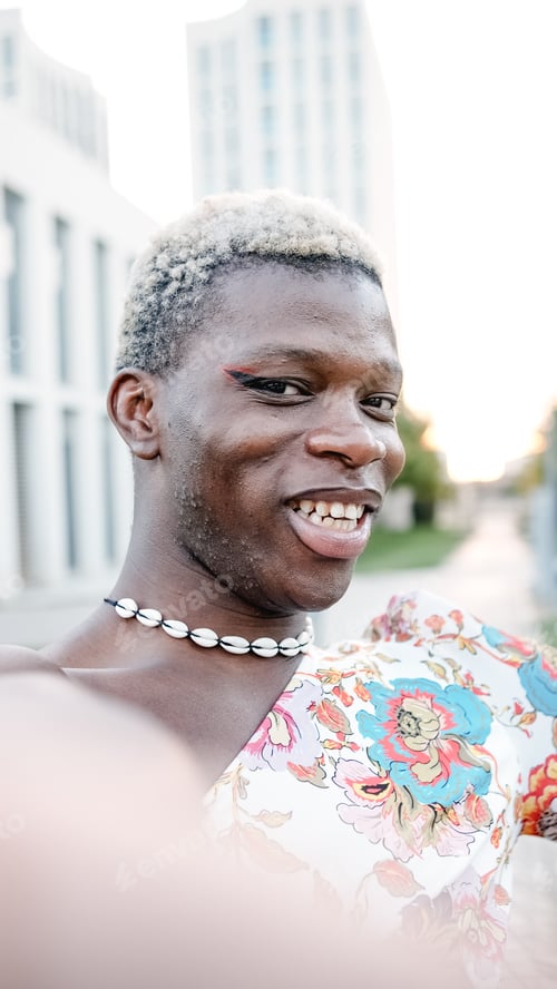 Preview: Smiled black homosexual man in dress looking at camera while taking selfie