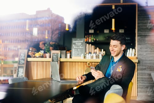 Preview: Smiling businessman listening to music while sitting with laptop at restaurant