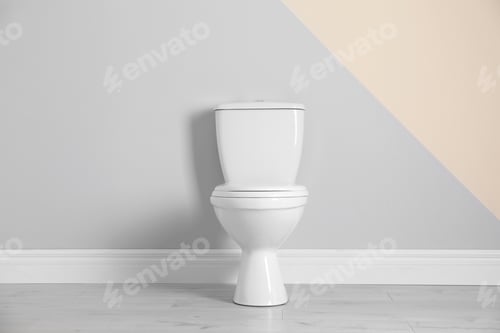 Preview: New toilet bowl near color wall indoors