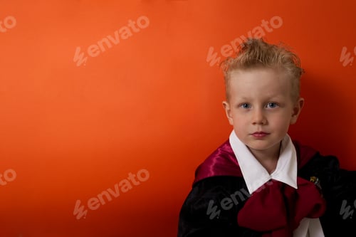 Preview: A boy in a vampire costume emotionally looks at the camera on an orange background