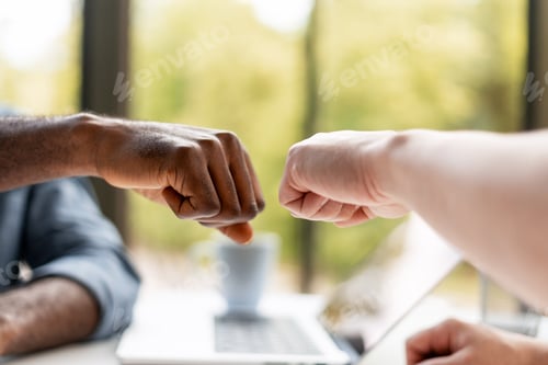 Preview: Coworkers fist bumping during a meeting in the office