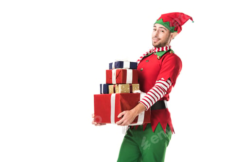 Preview: man in christmas elf costume looking at camera and carrying pile of presents isolated on white