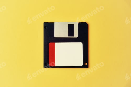 Preview: Black floppy diskette on yellow background. Vintage computer diskette, closeup