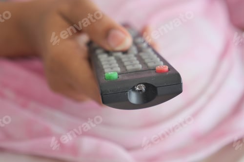Preview: close up of women hand holding tv remote.