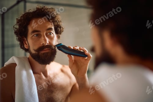 Preview: Mature man using electric razor while shaving in the bathroom.