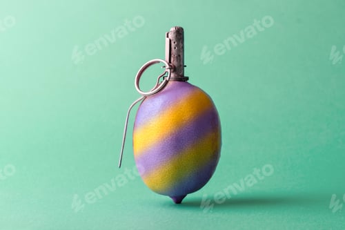 Preview: A lemon designed as a grenade with a metal detonator and ring, painted in yellow and purple stripes, on a green background.