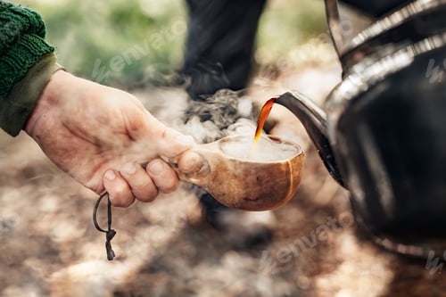 Preview: Close-up of hiker pouring hot coffee in wooden cup
