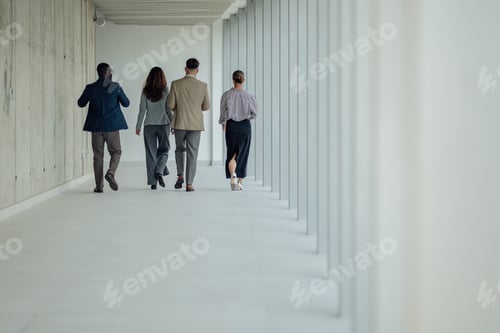 Preview: Businesspeople walking down modern office hallway