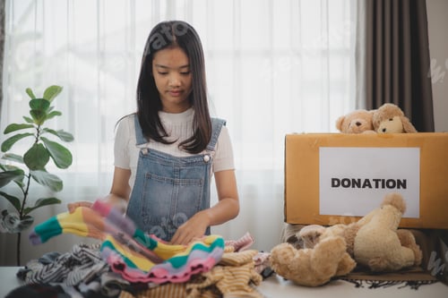 Preview: Recycling, Donation for poor, Asian girls packing objects at home, putting on stuff into donate box