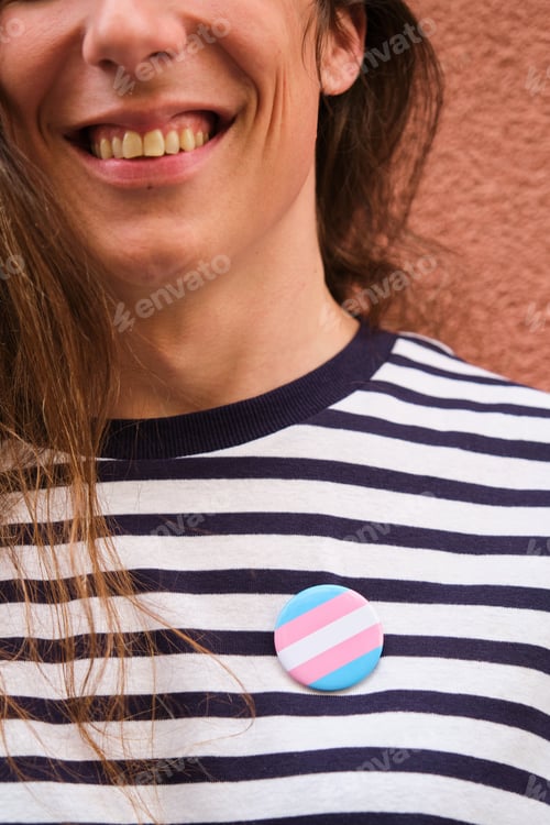 Preview: Close up of transgender woman with long hair and transgender flag pin.