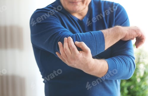 Preview: Mature man suffering from elbow pain at home
