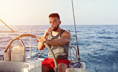 Visualização: Capitão branco caucasiano velejando com uma taça de vinho. Conceito de vela de atividade de lazer de verão