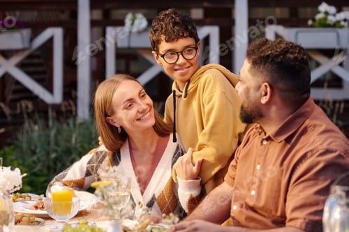 Preview: Multiethnic Family Enjoying Outdoor Dinner Together during Warm Evening