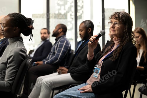 Preview: Senior woman participant in the audience asking questions during conference