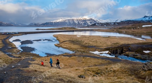 Preview: Family explores scenic landscape with mountains and river in Iceland during early evening