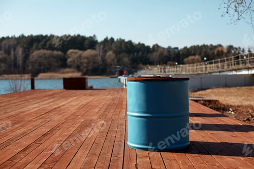 Preview: The blue barrel stands on the lake shore on a wooden pier. Spring landscape, blurred background