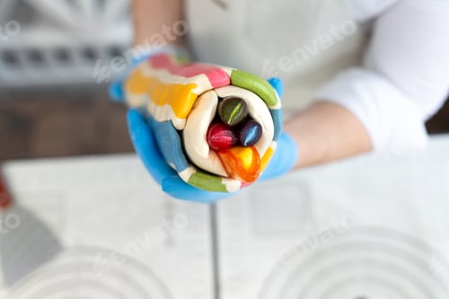 Preview: Chef glues multi colored hot caramel, lollipops on a stick. Handmade work. Lollipop with a pattern.