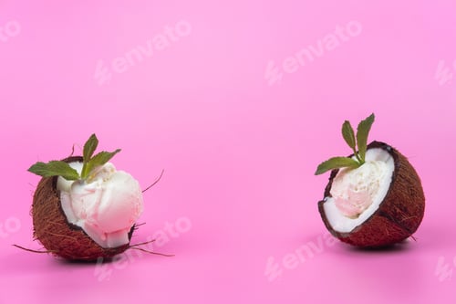 Preview: Vanilla ice cream balls in fresh coconut halves decorated with mint leaves on a pink background