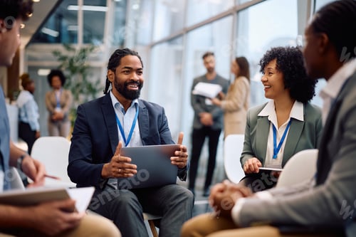 Preview: Happy black entrepreneur talking to his colleagues during business conference at convention center.