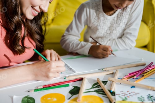 Preview: cropped view of happy babysitter drawing with kid in living room