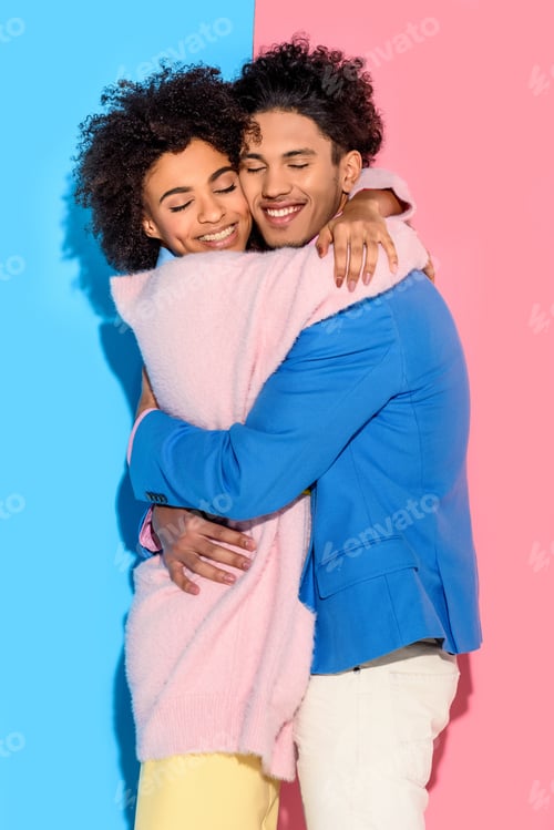 Preview: lovely young couple hugging each other on pink and blue background