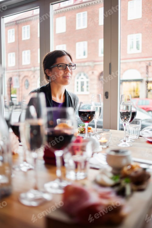 Preview: Woman looking away while sitting at dining table at restaurant