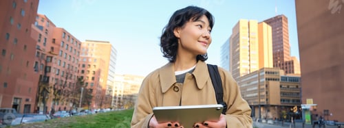 Preview: Happy young brunette girl, asian woman walks around city with tablet, goes to university with her