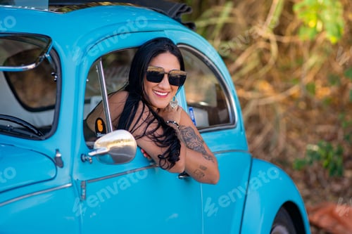 Preview: Young woman smiling from vintage blue car
