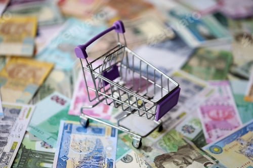 Preview: Supermarket trolley on many banknotes of different currency. Background of shopping worldwide