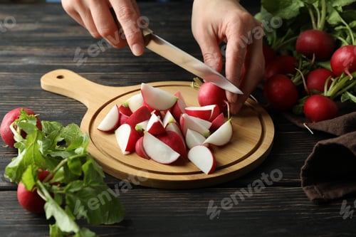 Preview: Woman cuts radishes on cutting board on wooden table