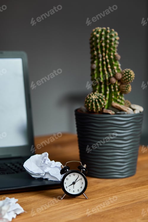Preview: Workplace, wooden office desk with clock, sheet of paper, laptop, notebook, crumpled paper
