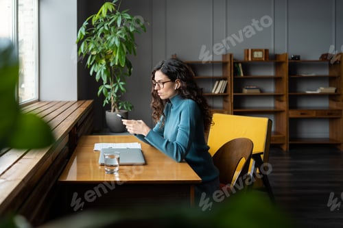 Preview: Woman copywriter freelancer using smartphone to check social media at workplace working remotely
