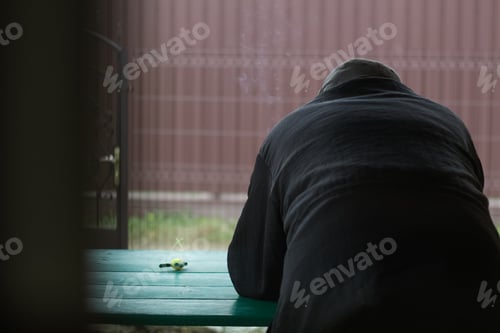 Preview: old man looking at the far outside. Image has a vintage effect. Back view of old man smoking and thi